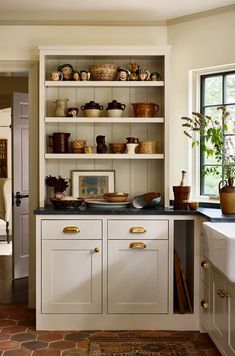 a kitchen filled with lots of white cupboards next to a sink and counter top