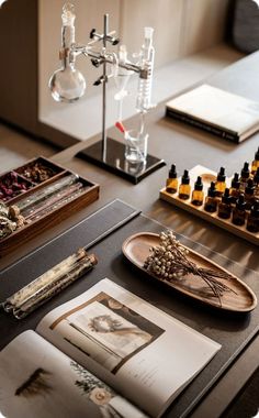 an assortment of bottles and other items on a table with books, glass flasks and candles