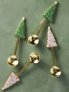 three spoons with christmas trees on them are sitting in the shape of spoons