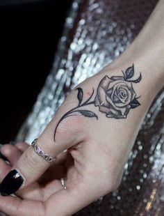 a woman's hand with a rose tattoo on it