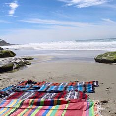 a blanket laying on top of a sandy beach next to the ocean