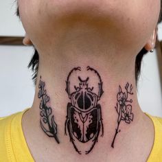 a woman with a scar on her neck has a beetle tattoo on it's neck