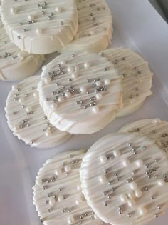 four cookies with pearls on them sitting on top of a white table covered in icing