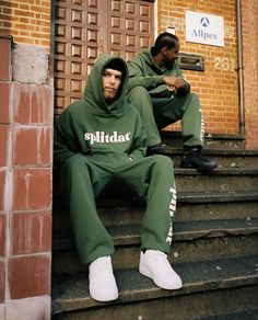 two men in green sweat suits sitting on steps