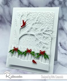 a white card with red ribbon and holly on it