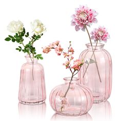 three vases with flowers in them on a white surface