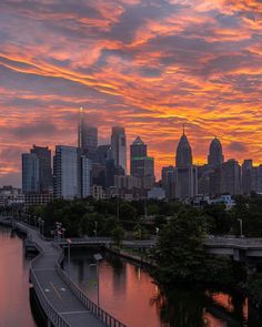 the city skyline is lit up at sunset with pink and orange clouds in the sky