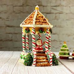 a gingerbread house is decorated with candy canes and other holiday decorations on a table