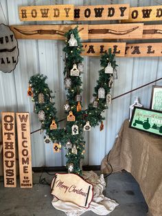 a christmas tree with ornaments on it in a room next to wooden signs and other decorations