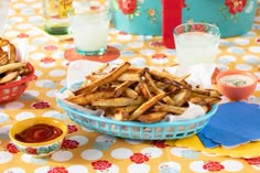 there is a bowl full of french fries on the table with other food items around it