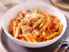 a white bowl filled with pasta covered in sauce and parmesan cheese