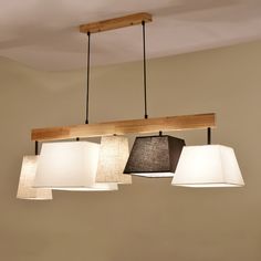 three lights hanging from a wooden beam above a table with books and flowers on it