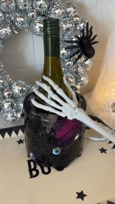 a wine bottle with skeleton hands sticking out of it sitting in front of a wreath