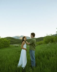 a man and woman standing in tall grass