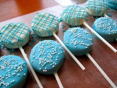 blue cake pops with white sprinkles are lined up on a wooden table