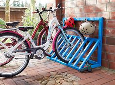 two bikes parked next to each other near a brick wall with a blue bike rack