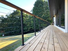 a wooden deck with black railings and trees in the background