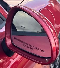 a red car with a cross on it's side mirror