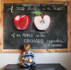 a little boy sitting on top of a table in front of a chalkboard