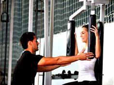 a man and woman doing pull ups in a gym together, with one holding on to the bar