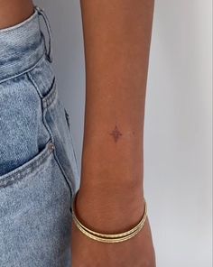 a woman's arm with a tiny star tattoo on the left side of her wrist