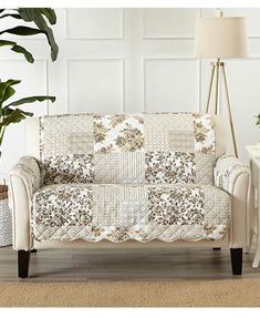 a white couch sitting next to a potted plant on top of a wooden floor