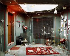 a room filled with lots of clutter and broken glassware on the floor next to a red rug