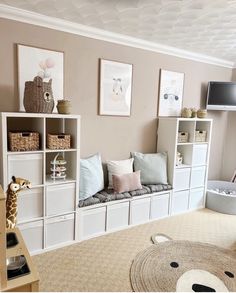 a living room filled with lots of white furniture and storage units next to a wall mounted flat screen tv