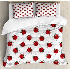 a bed with red ladybugs on it and white sheets