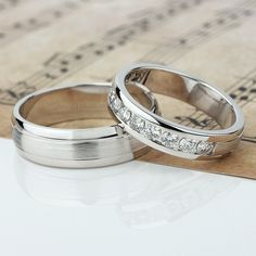 two wedding rings sitting on top of sheet music