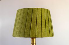 a green lamp with a gold base and pleated lampshade