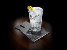 a glass with ice, lemon and water on a wooden table in front of a black background