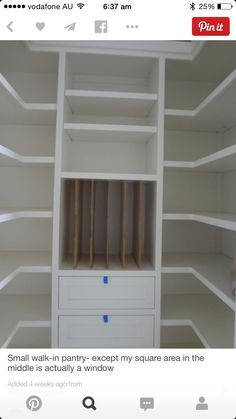 an empty white bookcase with some blue tape on the bottom shelf and two drawers