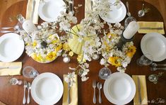 the table is set with white and yellow flowers