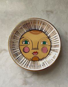 a yellow and white plate with a face painted on it