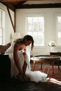 a woman in a white dress is kneeling on the floor next to a coffee table