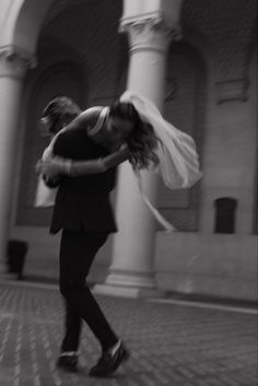 a man and woman are dancing in front of a building with columns on either side