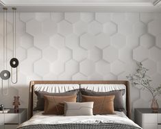 a bed with pillows and blankets on it in front of a wall that has hexagonal tiles