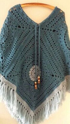 a blue crocheted shawl hanging from a wooden hanger