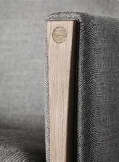 a close up view of a wooden object on a gray fabric couch with wood buttons