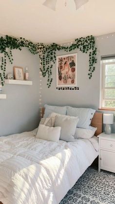 a white bed sitting in a bedroom next to a window with plants growing on it