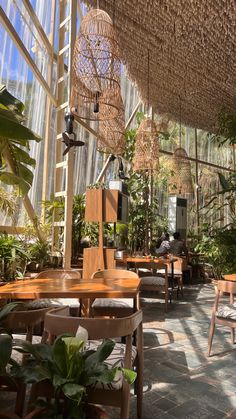 the inside of a greenhouse with tables, chairs and plants hanging from it's ceiling