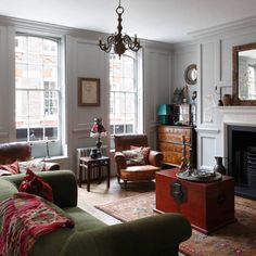 a living room filled with furniture and a fire place in front of a mirror on the wall