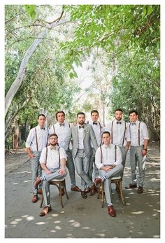 a group of men standing next to each other in front of some green trees and bushes