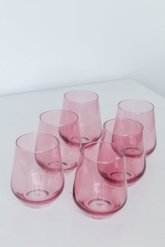 six pink glasses sitting on top of a white table