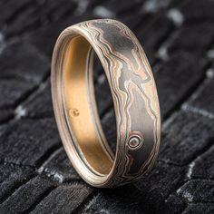 "* Price may vary depending on ring size, please inquire with us directly with your needed size for accurate pricing! This naturalistic feeling Mokume Gane band is shown in the Woodgrain pattern and the Firestorm metal combination, with a low dome profile, and an etched and oxidized finish. Firestorm features 14k red gold, 14k yellow gold, Palladium, and sterling silver.  This ring also has an added layer of palladium on top for a more overall gray look. Pattern: Woodgrain Palette: Firestorm  Finish: Etched and Oxidized Profile: Low Dome Width Shown: 7mm Size Shown: 12.5 Add Ons: Palladium Topsheet Price does NOT include stones or setting fees. We care about customer service and would like to hear from you! Please contact us to help create your treasured item, we take your concerns and req Artisan Untreated Jewelry For Wedding, Artisan Untreated Wedding Jewelry, Round Patina Rings For Anniversary, Heirloom Etched Promise Rings, Artisan Engraved Rings For Formal Occasions, Adjustable Engraved Round Bands, Heirloom Etched Round Band Rings, Adjustable Engraved Bands, Adjustable Engraved Band