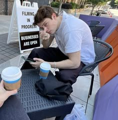 a man sitting at a table with a cup of coffee and cell phone in his hand