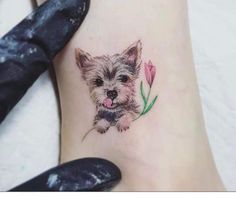 a small dog with a flower tattoo on the ankle