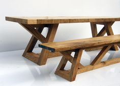 a wooden bench sitting on top of a white floor next to a table with two benches underneath it