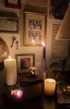 two lit candles are sitting on a table next to some pictures and other things in the room